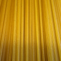 Close-up van goudgele, ongekookte glutenvrije spaghetti met zichtbare lengtestrepen.